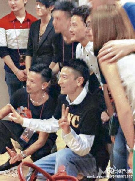 刘德华穿着歌迷会会服，跟一众工作人员合照。